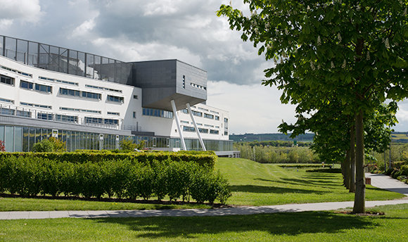 A view of Queen Margaret University Campus from outside with foliage in the foreground