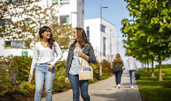 Two Queen Margaret University students walking down an outdoor path on campus
